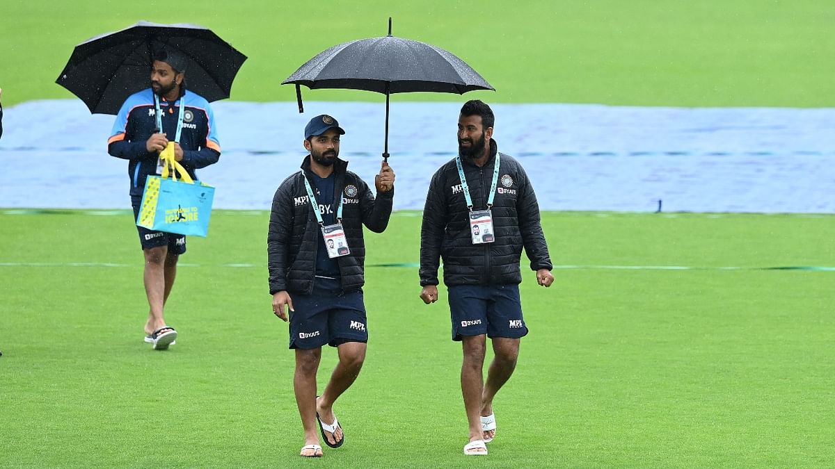 Ajinkya Rahane and Cheteshwar Pujara walk on the pitch as rain stops play on the fourth day. Credit: AFP Photo
