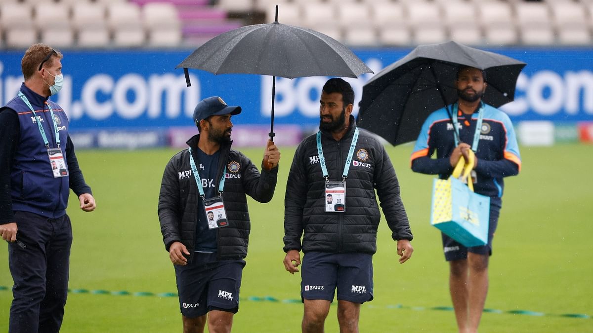 Ajinkya Rahane, Cheteshwar Pujara and Rohit Sharma walk on the field as rain stops the match. Credit: Reuters Photo