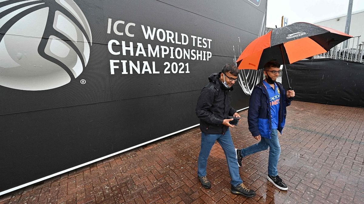 Indian fans walk in the rain on the fourth day of the ICC World Test Championship Final between New Zealand and India at the Ageas Bowl in Southampton, southwest England. Credit: AFP Photo