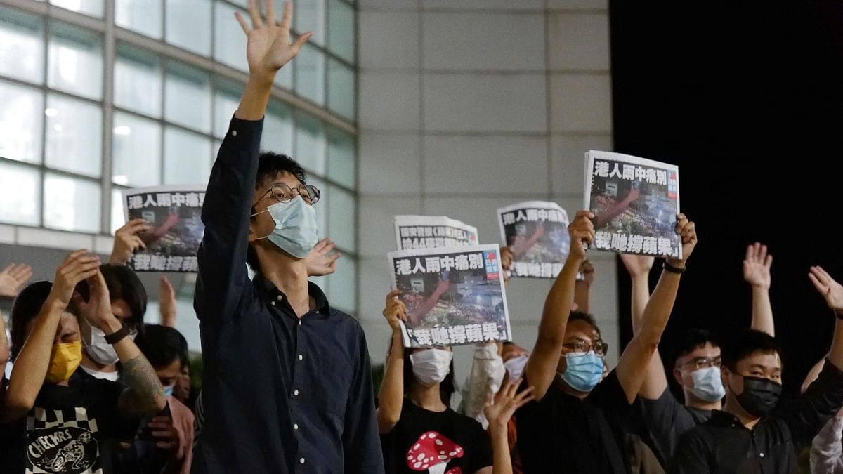 Apple Daily journalists show the last-edition copies while acknowledging the supporters gathered outside their office in Hong Kong. Credit: AFP Photo
