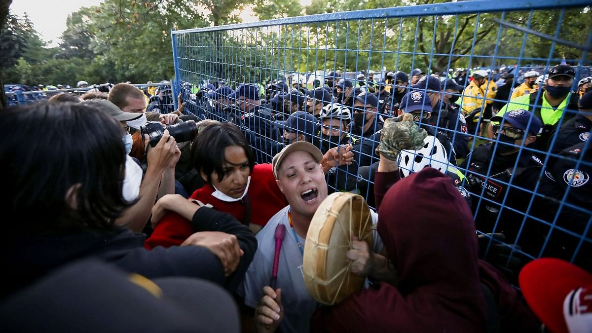 Police officers push people out of a barricade after the eviction of a homeless encampment at Trinity Bellwoods Park in Toronto. Credit: Reuters photo