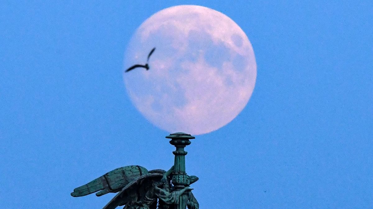 The full moon is pictured behind sculptures on the Saint Icaas's cathedral in Saint Petersburg. Credit: AFP Photo