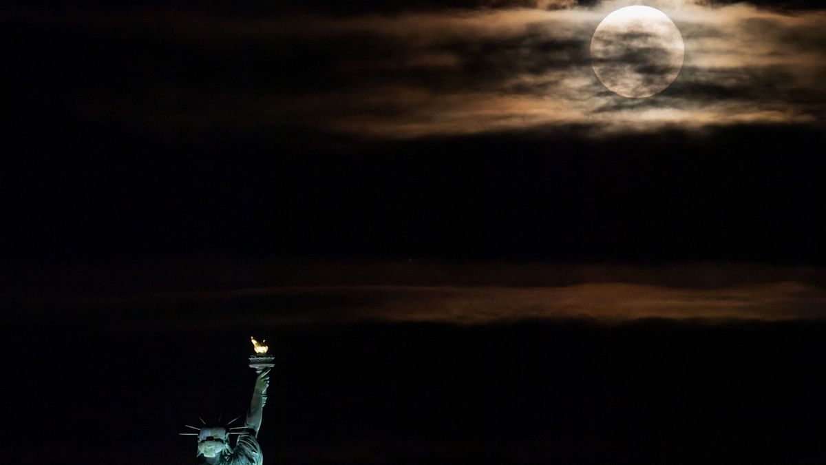 The Strawberry Moon rises from behind the Statue of Liberty in New York City. Credit: AFP Photo