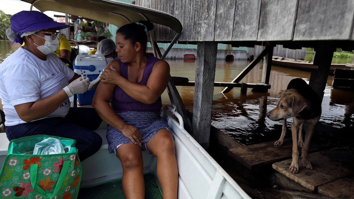 Marair Queiroz receives the Oxford/AstraZeneca vaccine against Covid-19 from municipal health worker Neuda Sousa during a flood by the rising Solimoes river, one of the two main branches of the Amazon River, in Anama, Amazonas state, Brazil. Credit: Reuters Photo