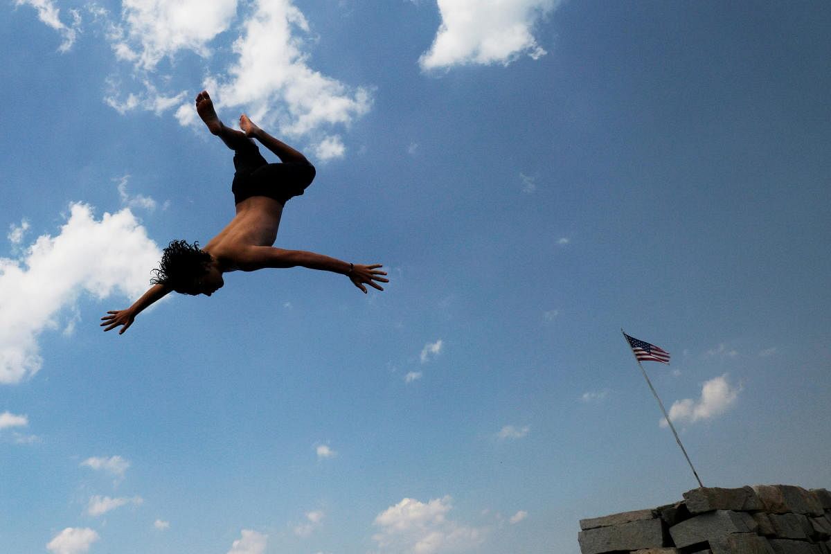 Kids jump off a breakwater into the ocean on a hot summer day during a projected heatwave in Gloucester, Massachusetts. Credit: Reuters Photo