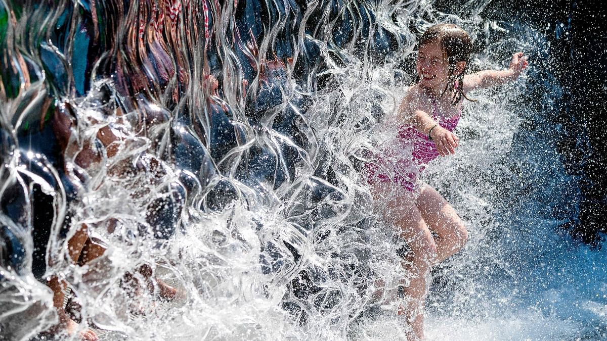 A young girl splashes through a waterfall at a park as a heatwave moves over much of the United States.