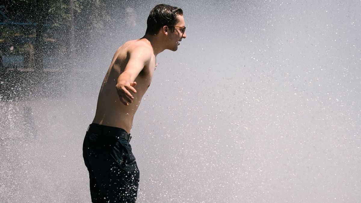 A man cooling down by standing in front of a fountain during heat wave in US.