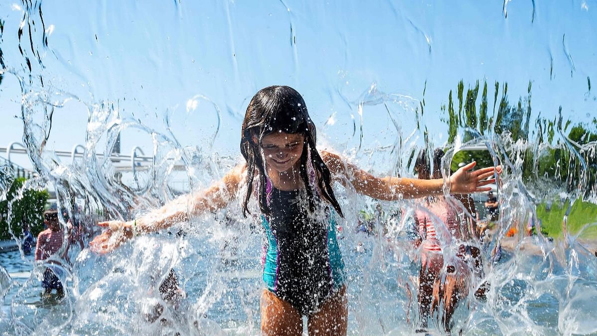 Children play in water as they try to escape the heat.