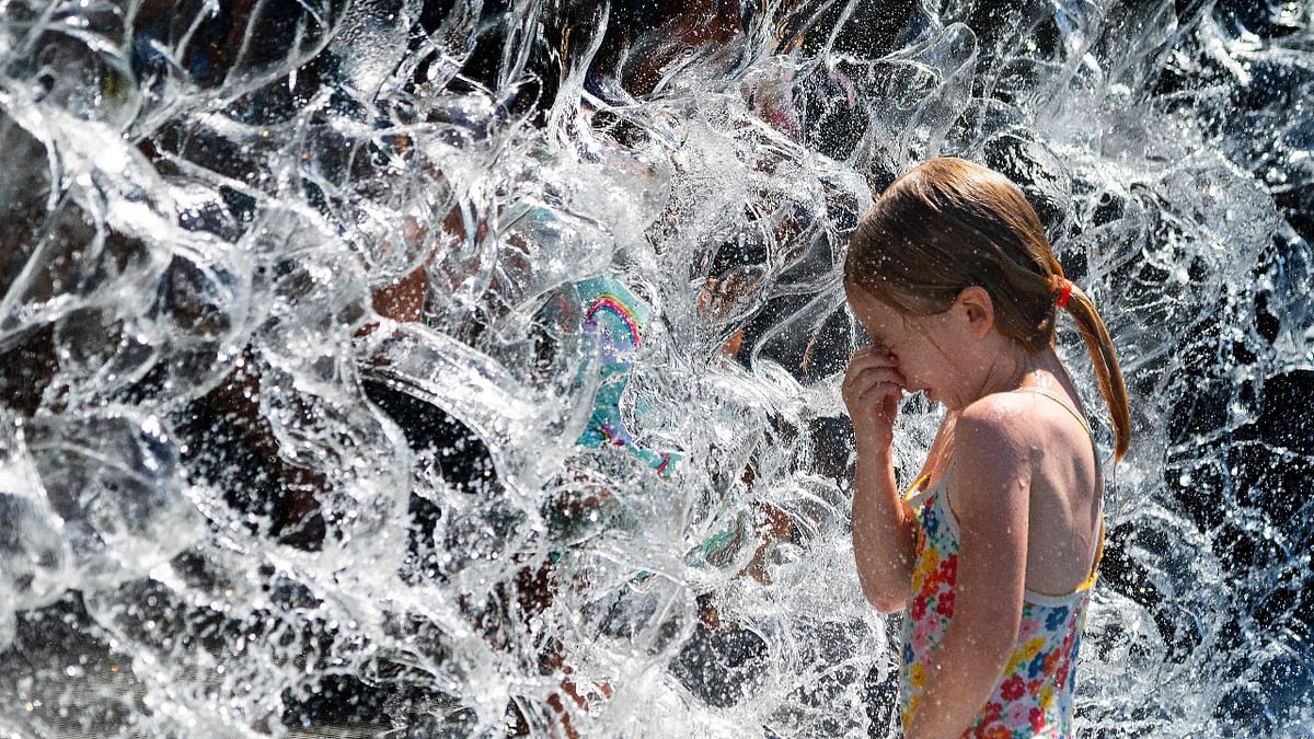 A young girl holds her nose before splashing through a waterfall at a park in Washington, DC.