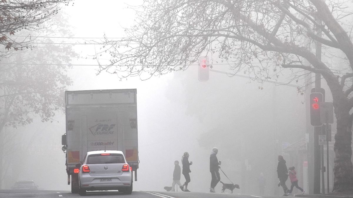 Sydneysiders under a heavy fog cross the main road in north Sydney on July 2, 2021. Credit: AFP Photo