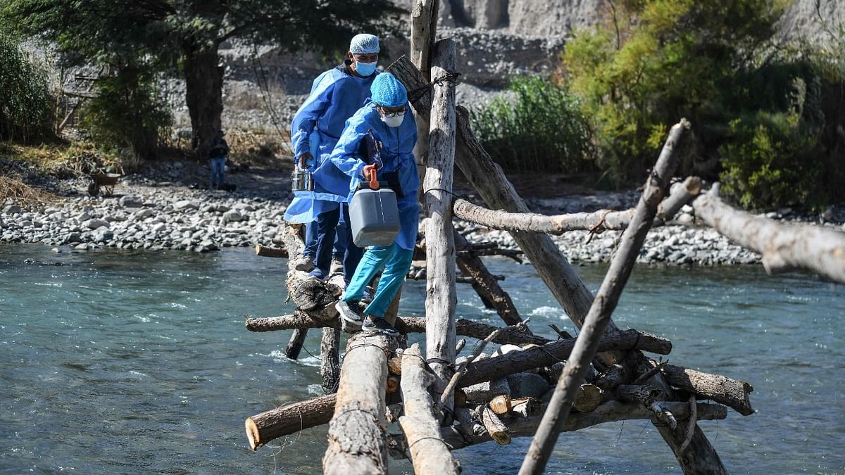 Health workers cross the Camana River to inoculate elderly citizens with doses of the Pfizer-BioNTech vaccine against Covid-19, in Arequipa, southern Peru. Credit: AFP Photo