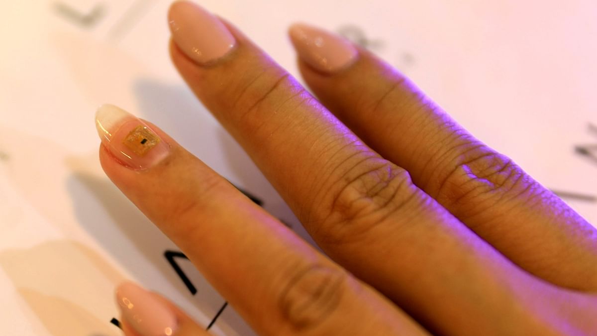 A customer gets a microchip attached to one of her nails at Lanour Beauty Lounge in Dubai, United Arab Emirates.