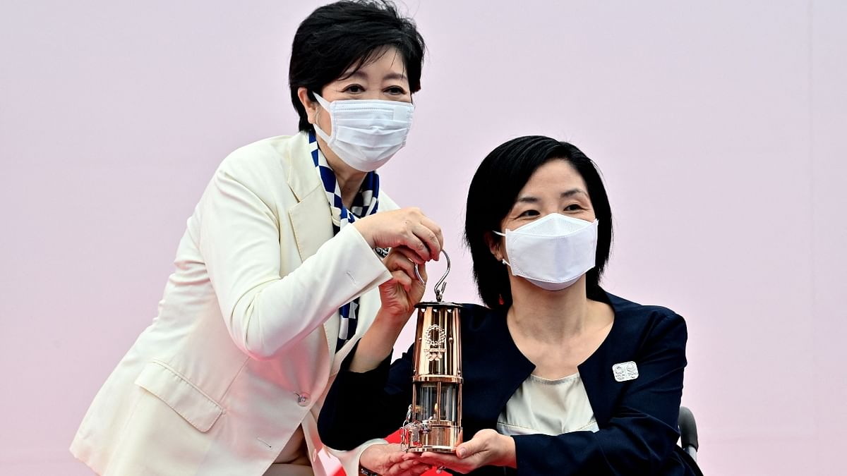 Former Japanese paralympian, Aki Taguchi hands over the Olympic flame to Tokyo governor Yuriko Koike (L) during the unveiling ceremony of the Olympic flame at the Komazawa Olympic Park General Sports Ground on the first day of the torch relay in Tokyo. Credit: AFP Photo