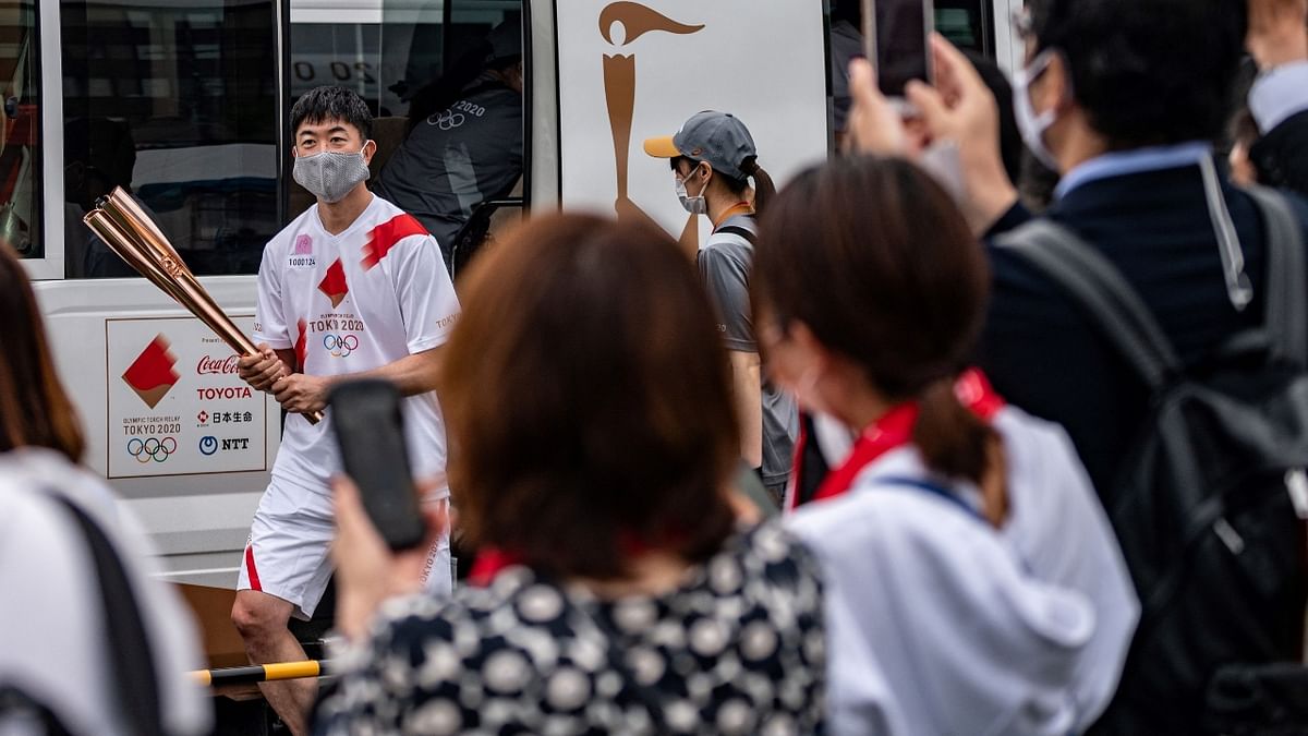 Torchbearer Shinichi Okada disembarks from an official Tokyo 2020 bus before the lighting ceremony of the Olympic flame at Machida Shibahiro, on the first day of the torch relay in Tokyo. Credit: AFP Photo