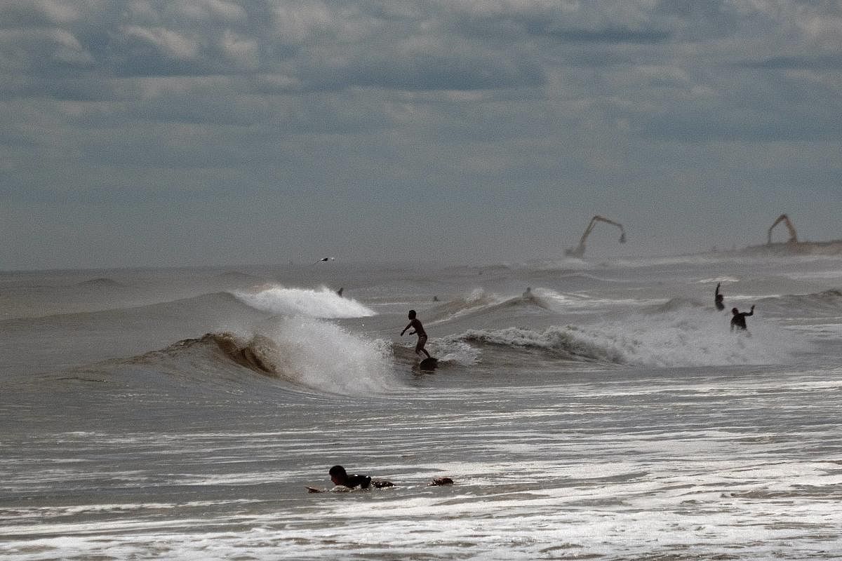 Surfers take advantage of unusually high surf due to Tropical Storm Elsa at Rockaway Beach in Queens in New York City. After coming ashore in Florida, Elsa has moved up the coast and is affecting major cities in the Northeast. Credit: AFP Photo