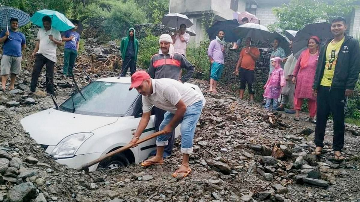 In this photo, you can see villagers trying to remove a car stuck in the rubble after heavy rains at Bajaura in Kullu.