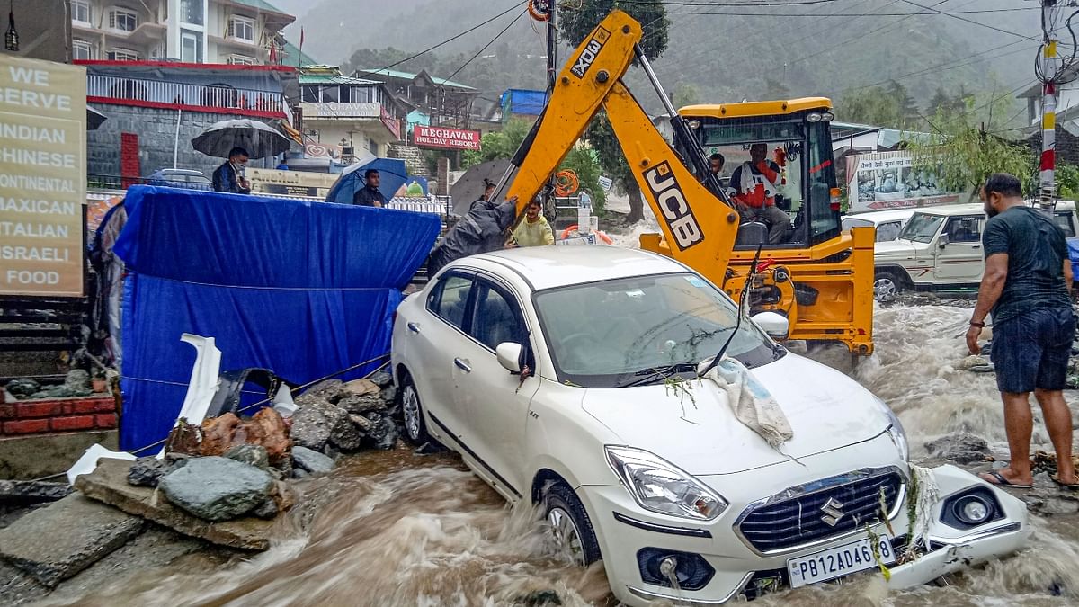 A crane is seen removing a vehicle stuck in flood water near Bhagsunag, in McLeodganj near Dharamshala.