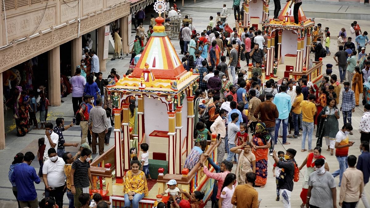 Devotees stand near chariots inside the premises of a temple on the eve of the annual 'Rath Yatra' festival, in Ahmedabad. Credit: PTI Photo