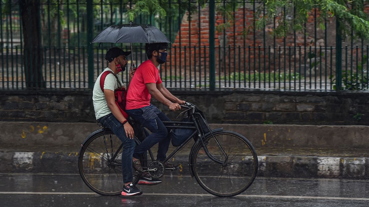 Commuters carry an umbrella during rain as monsoon reaches New Delhi. Credit: PTI Photo