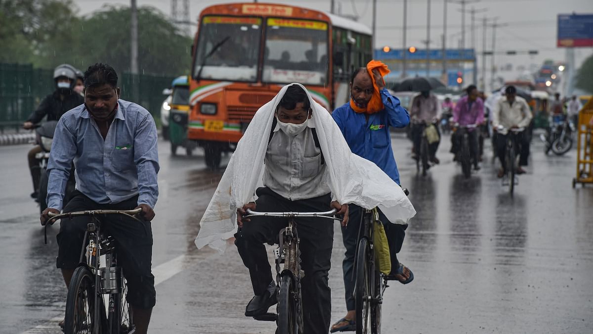 People are seen riding bicycles amid the rain in New Delhi. Credit: PTI Photo