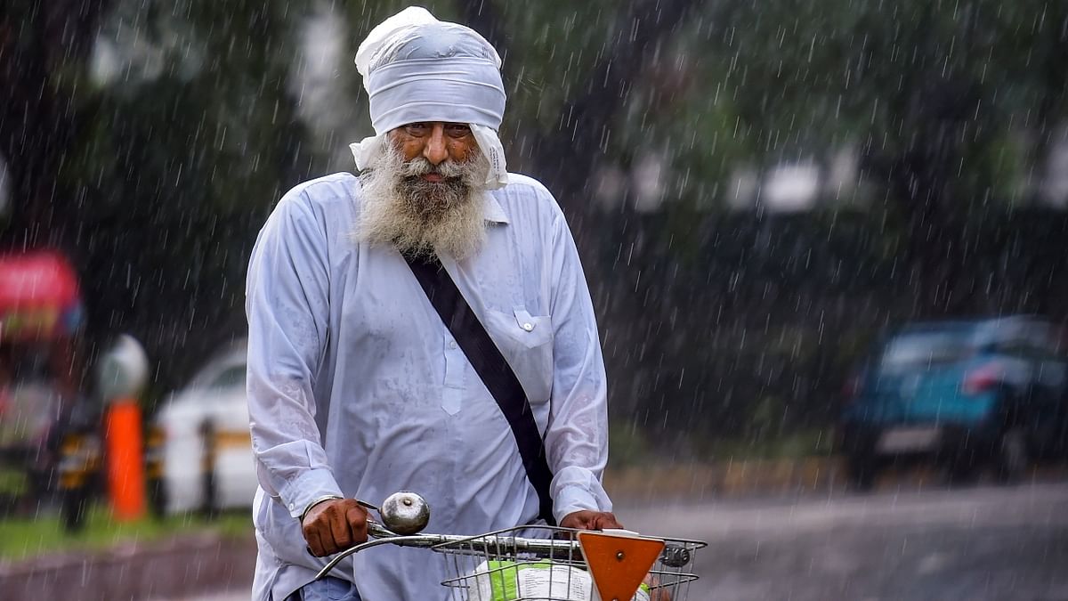 An elderly Sikh rides on a bicycle as he makes his way during heavy rains in New Delhi.