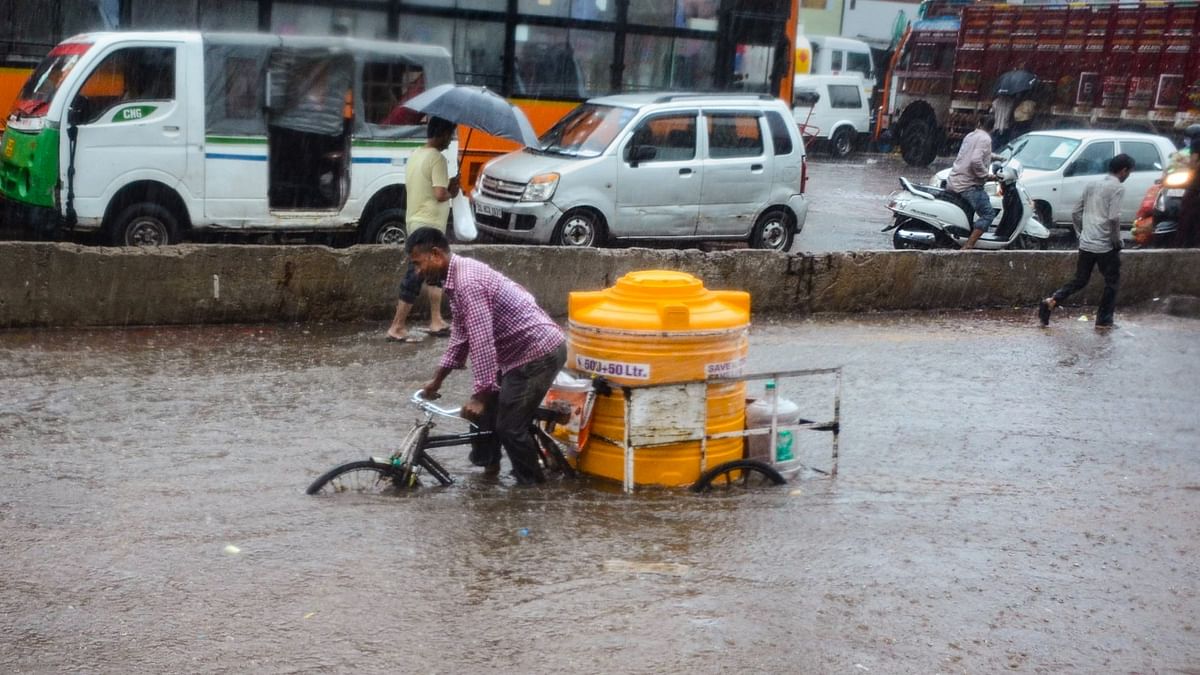 A man on a tricycle rickshaw wades through a waterlogged road during heavy rains at the Azadpur in New Delhi.