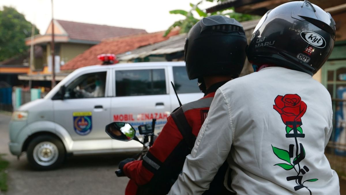 A volunteer biker wears a jacket depicting roses while escorting an ambulance to a cemetery in Jakarta, Indonesia.