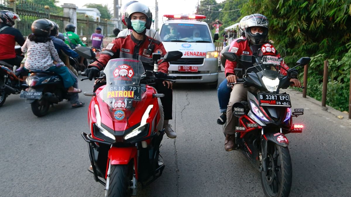 Volunteer bikers escort an ambulance to a cemetery as Covid-19 cases surge in Jakarta, Indonesia.