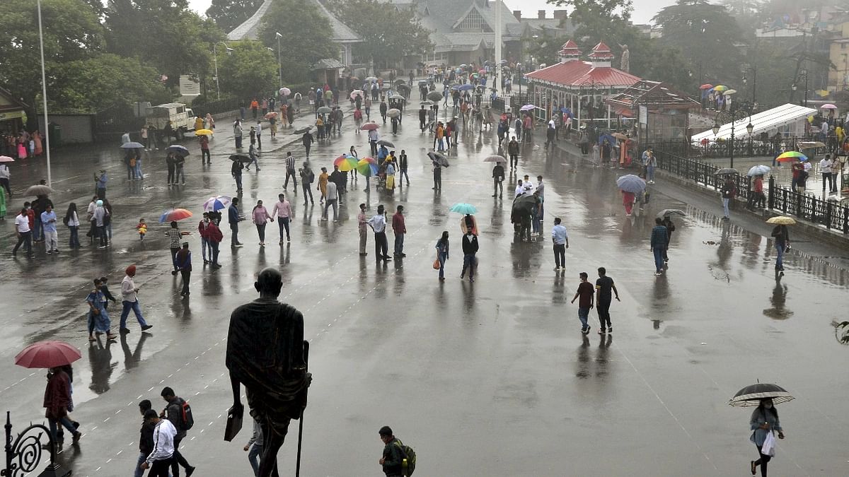 Travellers are seen enjoying the drizzle at Ridge in Shimla. Credit: PTI Photo