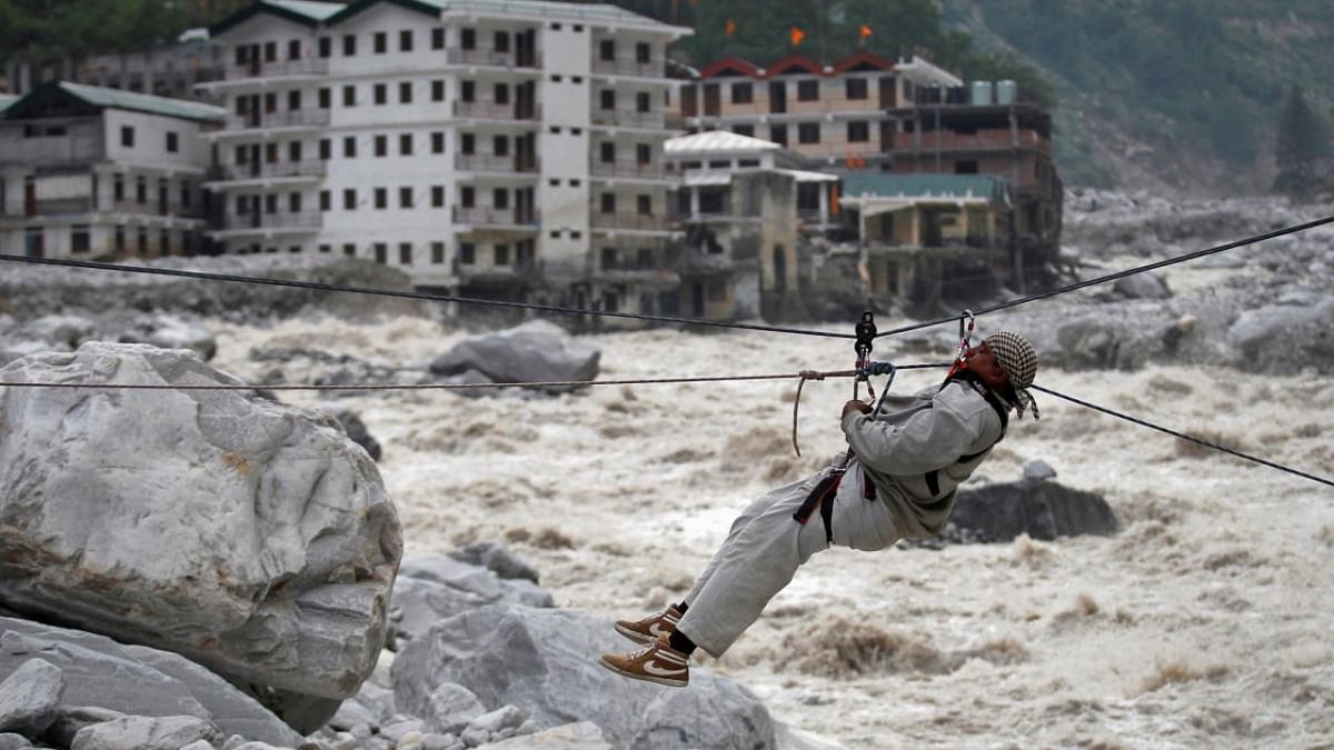 A man is pulled across to safety on a rope, as damaged buildings and the Alaknanda river are seen in the background, during a rescue operation in Govindghat in the Himalayan state of Uttarakhand June 23, 2013. (Credit: Reuters Photos/Danish Siddiqui)