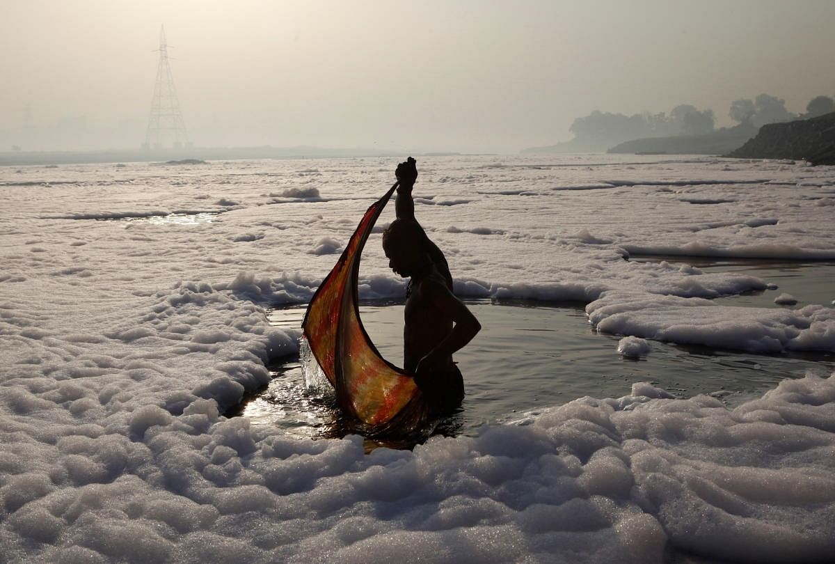 A Hindu devotee wraps his cloth after a ritual dip in the polluted Yamuna river in New Delhi on March 21, 2010. (Credit: Reuters Photos/Danish Siddiqui)