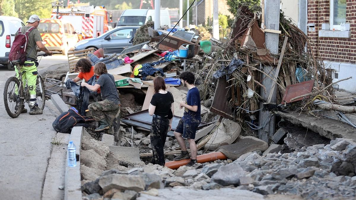 Residents look through rubble for their belongings in a street following heavy rainfall that caused severe flooding in the area, in Vaux-sous-Chevremont, Belgium. Credit: AFP Photo