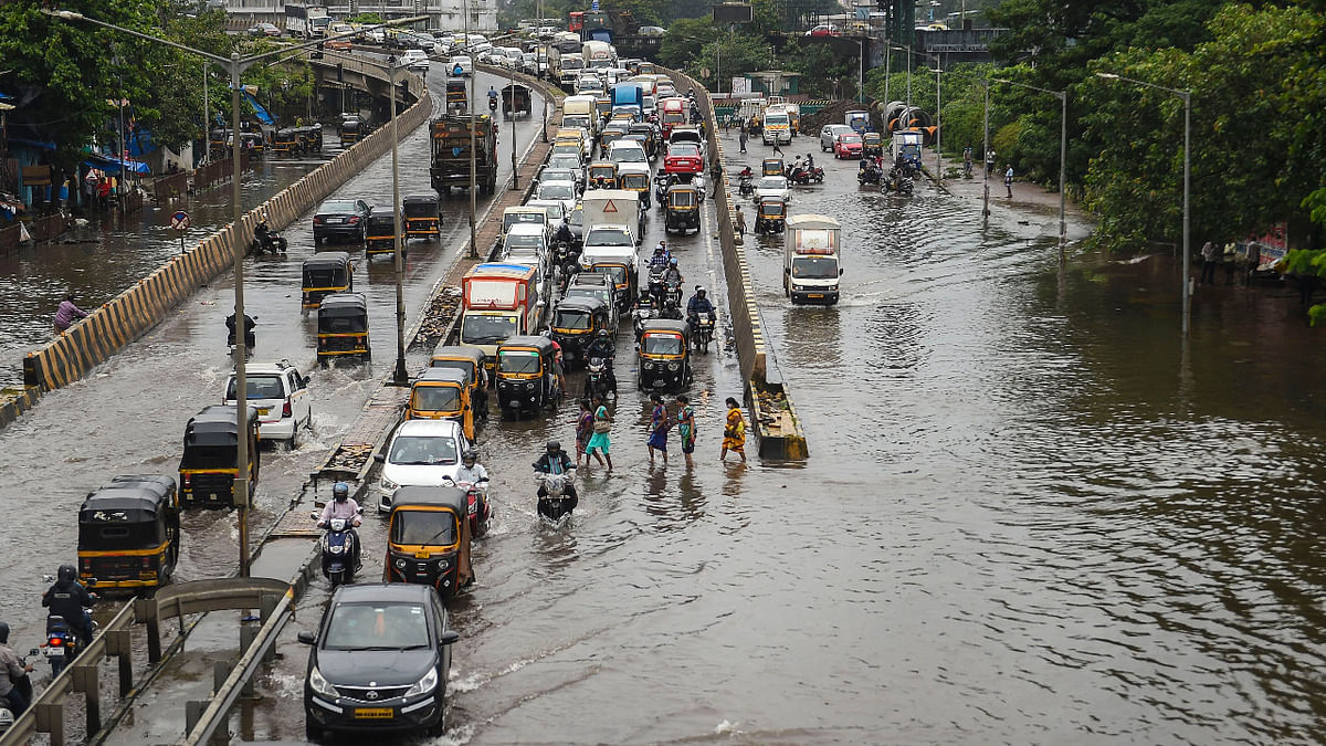 Commuters navigate through a waterlogged street as heavy rain continues at Santacruz- Chembur Link Road, in Mumbai. Credit: PTI Photo