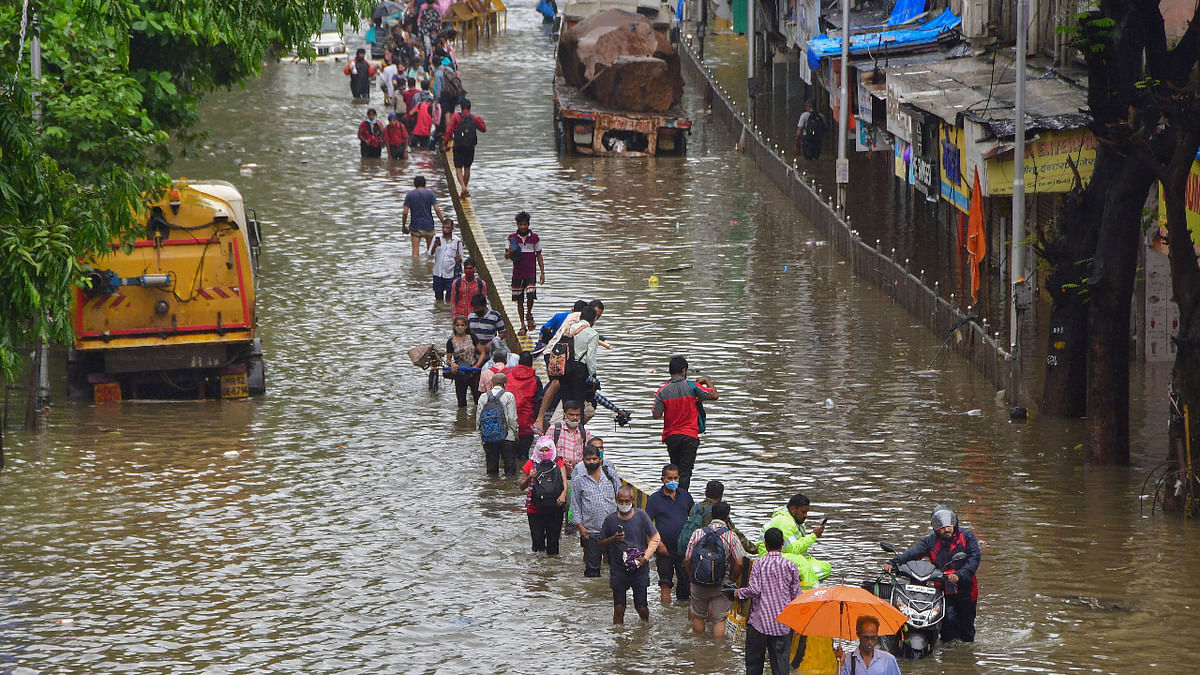 Commuters wade through a waterlogged street after heavy rain at Dadar in Mumbai. Credit: PTI Photo