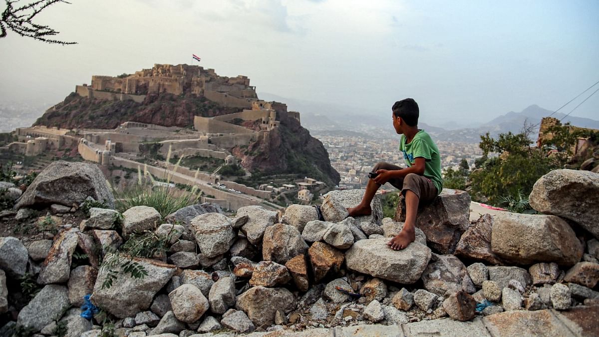 A boy looks at a giant Yemeni flag flying at the historic 12th cehntury citadel of al-Qahira in Yemen's third city of Taez. Credit: AFP Photo