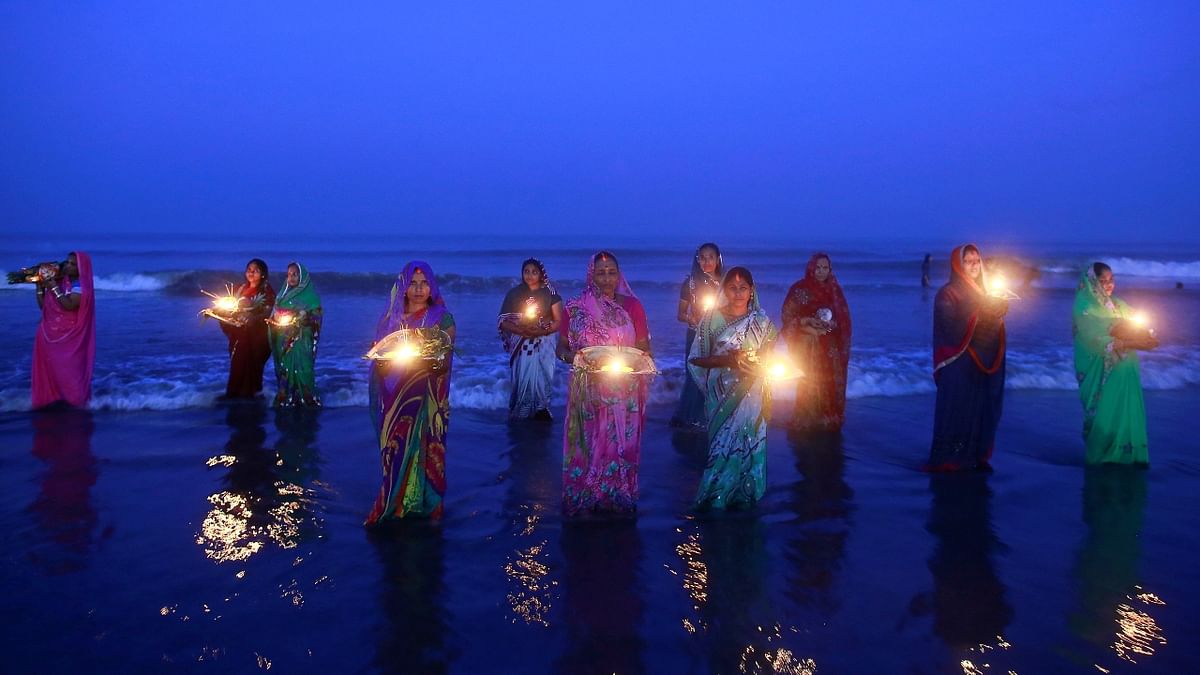 Hindu women pray while standing in the waters of the Arabian Sea as they worship the Sun during the religious festival