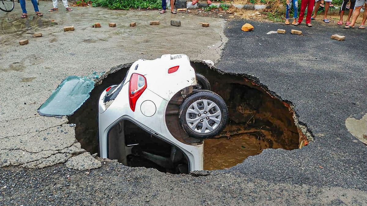 A car falls into a cavity after a road caved in at Dwarka in New Delhi on Monday. credit: PTI Photo