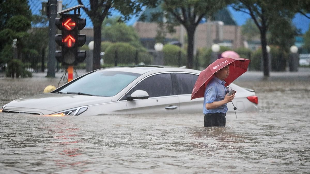 A man tries to get past a submerged car along a flooded street following heavy rains. Credit: AFP Photo