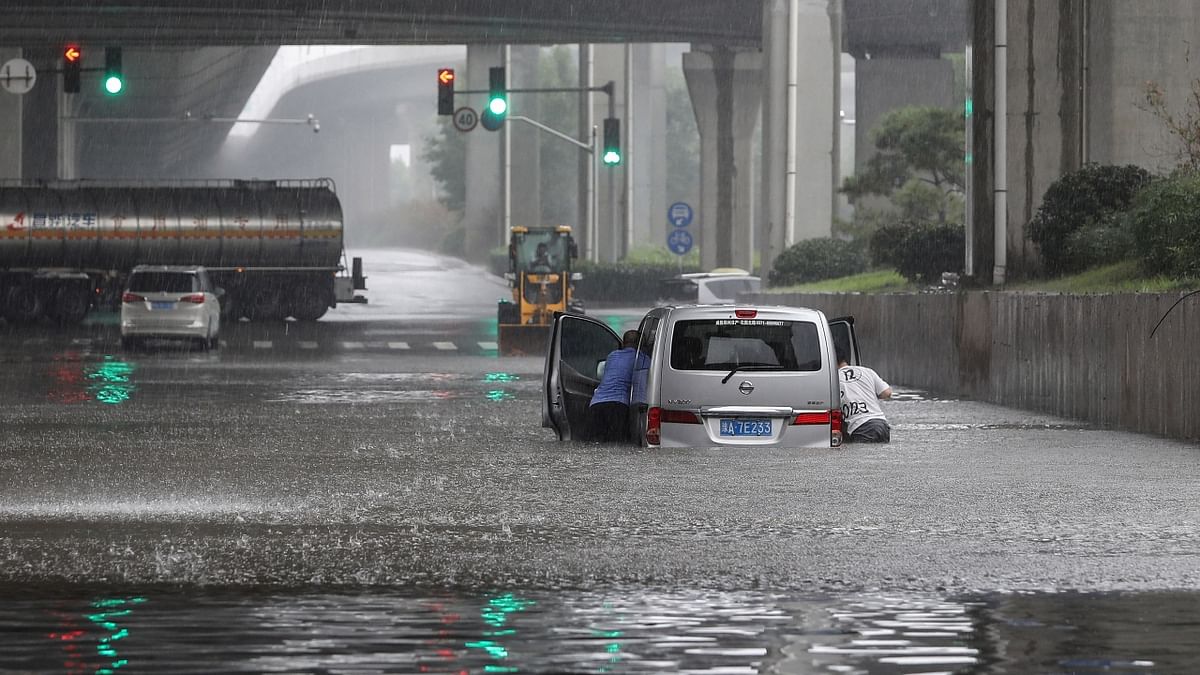 People pushing a van through flood waters along a street in Zhengzhou. Credit: AFP Photo