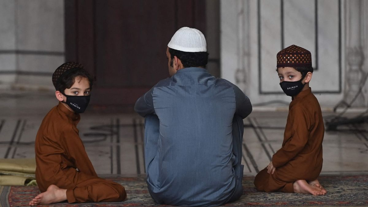 Eid al-Adha celebrations were subdued in India and in several parts of the world with no major congregational prayers and community feasts over fears of triggering a third wave of the coronavirus. A Muslim man sits with his children after offering prayers during the Eid al-Adha festival at the Jama Masjid in New Delhi. Credit: AFP Photo