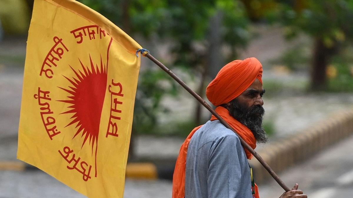 A protesting farmer holds a flag as he joins the protest in New Delhi. Credit: AFP Photo