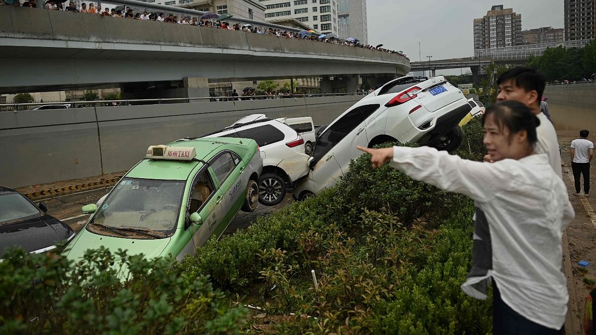 People look at cars sitting in floodwaters following heavy rains, in Zhengzhou in China. Credit: AFP Photo
