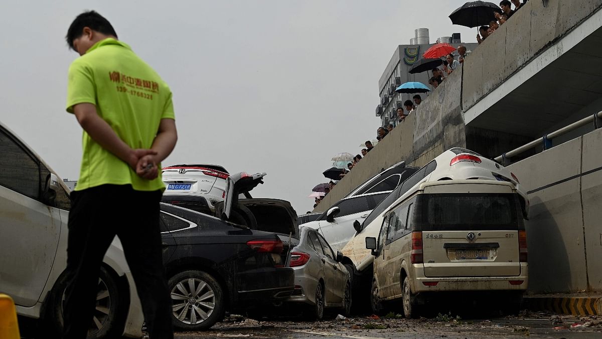People look at cars sitting in floodwaters following heavy rains, in Zhengzhou in China. Credit: AFP Photo