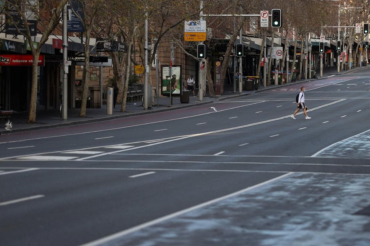 A lone man wearing a protective face mask crosses an empty street during a lockdown to curb the spread of a coronavirus disease (COVID-19) outbreak in Sydney. Credit: Reuters Photo