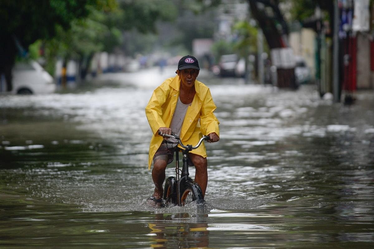 A man on a bicycle wades through a flooded street in Manila, Philippines. Credit: Reuters Photo