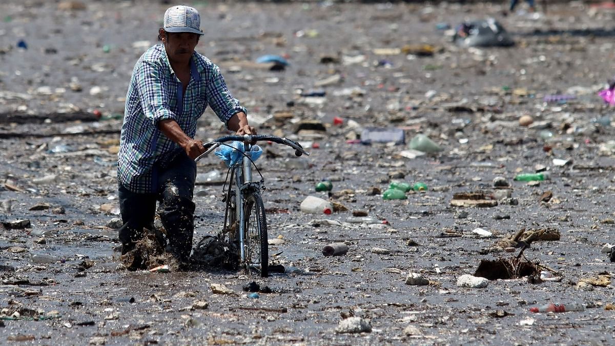 A man with a bicycle wades amid mud after heavy rains overflowed the El Seco stream, in Zapopan, Jalisco state, Mexico. Credit: AFP Photo
