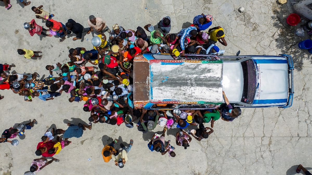 People gather around a car where volunteers distribute food to refugees at a shelter for families displaced by gang violence at the Saint Yves Church in Port-au-Prince, Haiti. Credit: Reuters photo
