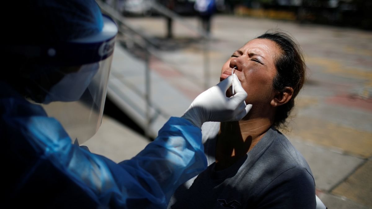 A medical worker takes a swab sample from a woman to test for the coronavirus disease (Covid-19), after the government set up testing booths in San Rafael Cedros, El Salvador. Credit: Reuters photo