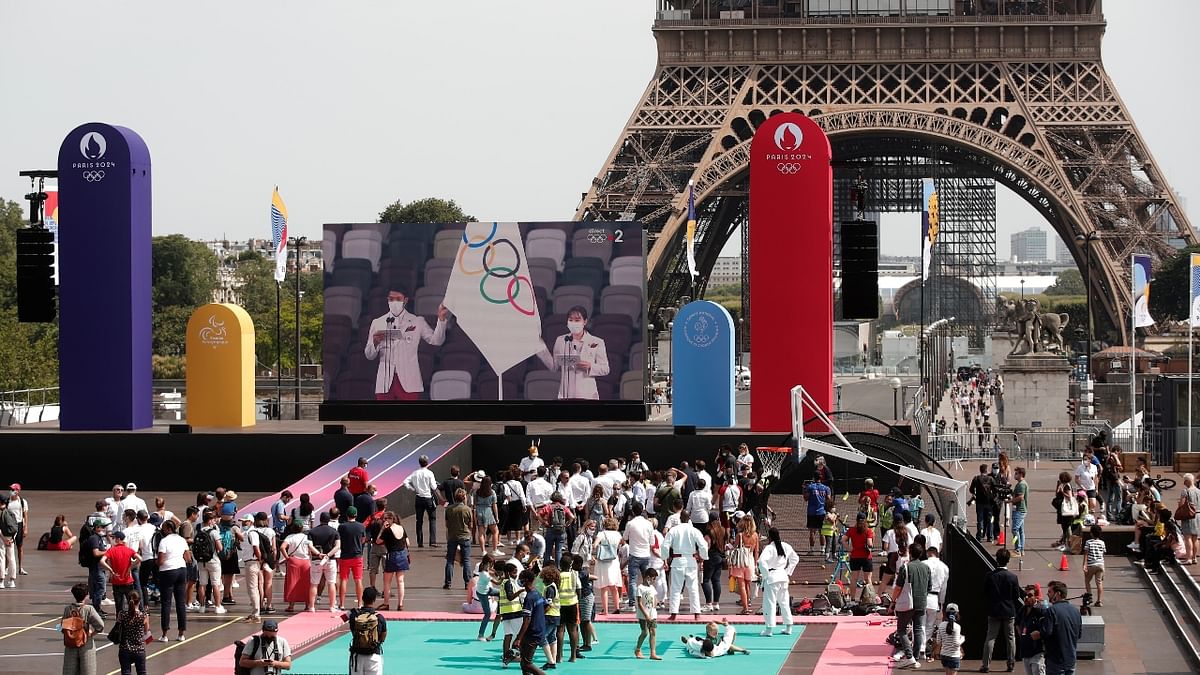 People watch the Tokyo 2020 Olympic Games opening ceremony displayed on a screen at the Trocadero Gardens, next to the Eiffel Tower, in Paris, France. Credit: Reuters Photo