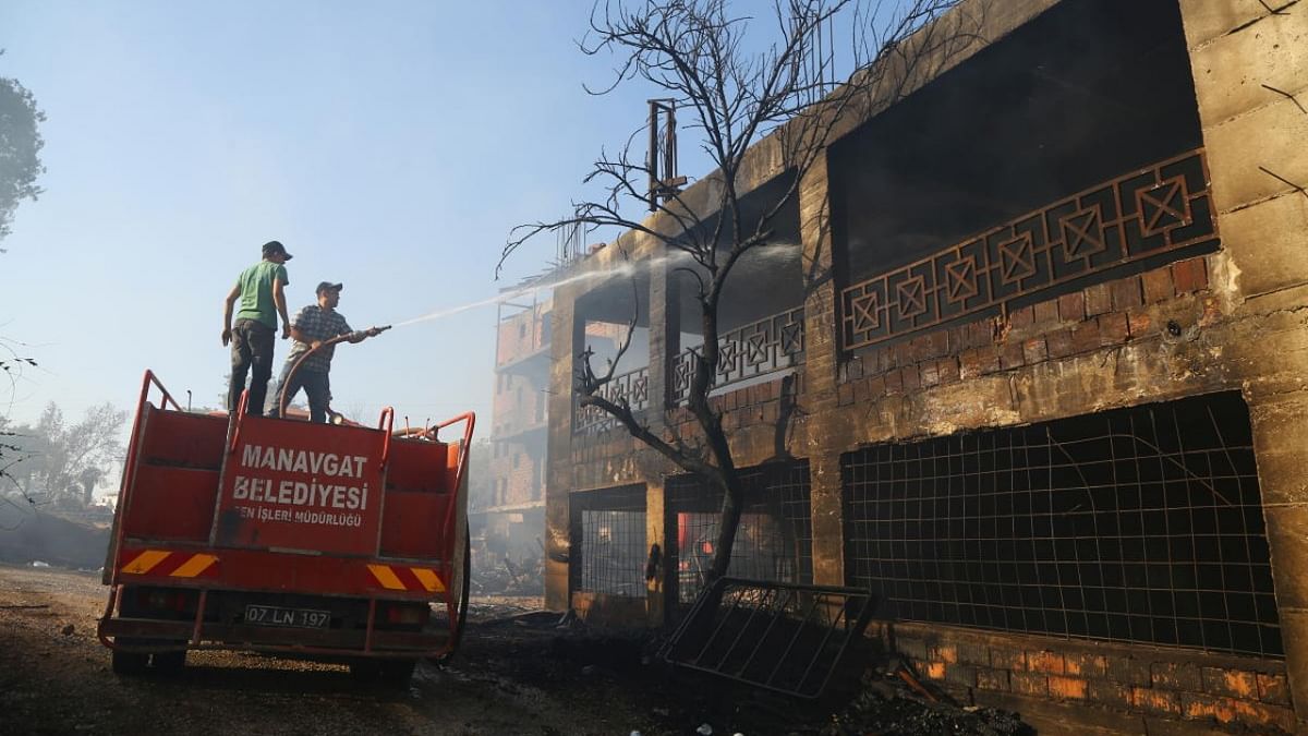 A firefighter cools a burnt house as a massive forest fire spread to the town of Manavgat, 75 km (45 miles) east of the resort city of Antalya, Turkey. Credit: Reuters photo